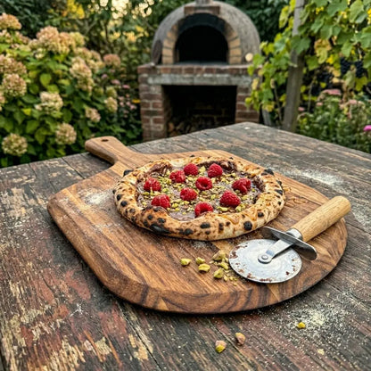 Pizza en Nutella, Framboises fraîches, Pistaches croquantes sur une pelle à pizza acacia